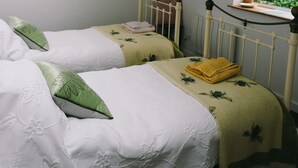 A bedroom with two beds, a window with a view, a radiator, and a mirror on the wall. - woodland cottage (barnstaple)