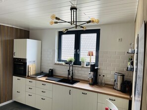 Eine moderne Küche mit Backofen, Spüle und einem Fenster mit Jalousien.