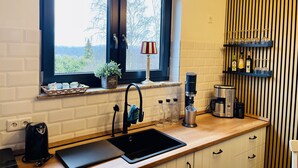 Une cuisine moderne avec une fenêtre, un évier, une machine à café et une étagère remplie de bouteilles.