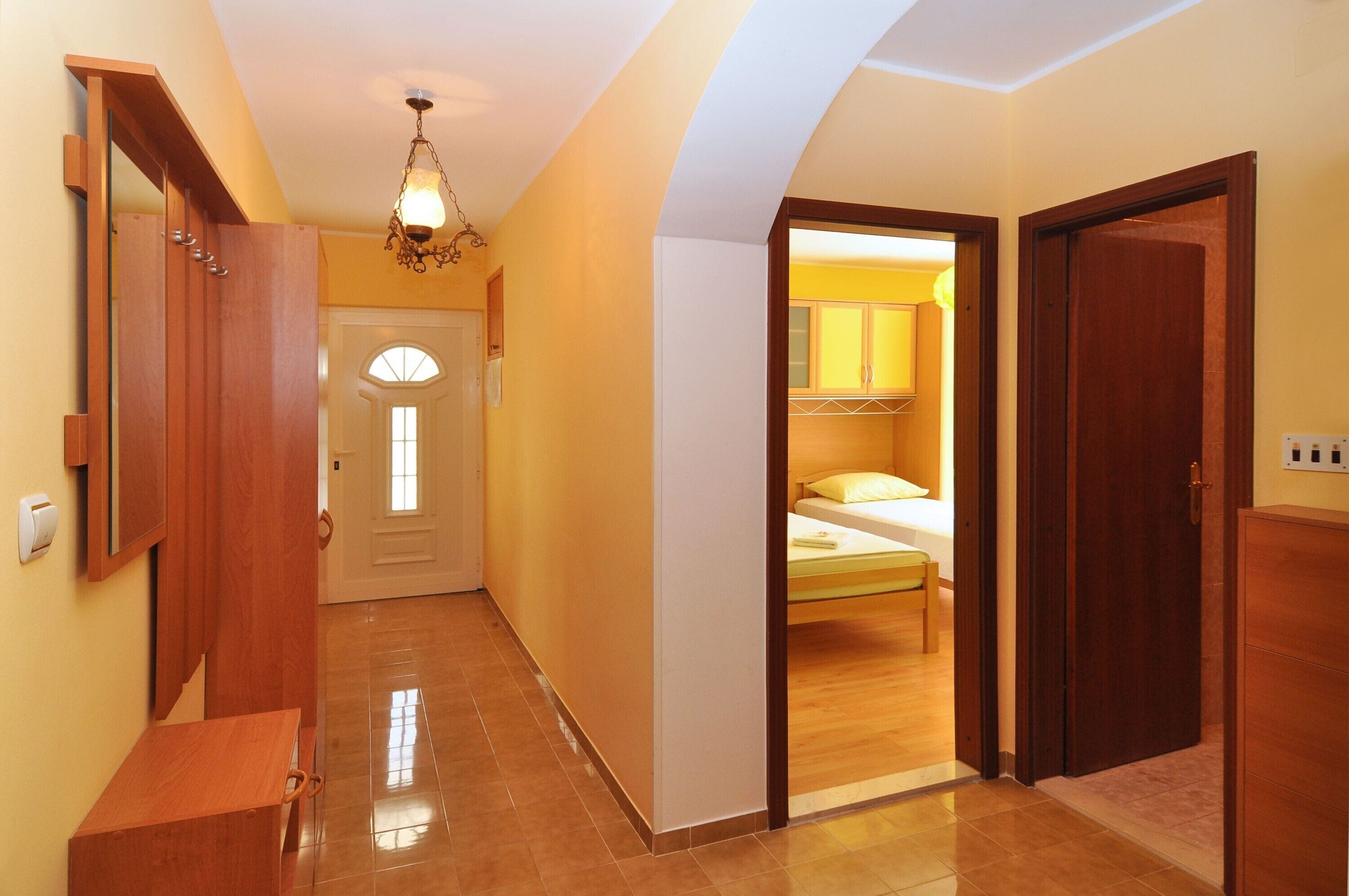 A hallway with a wooden bench, a door leading to a bedroom, and a ceiling light fixture.