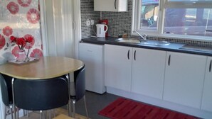 Una cocina compacta con armarios blancos, encimera negra, un lavabo y una ventana con vistas al exterior.