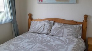 Una cama con cabecera de madera y dos almohadas con diseño de hojas.