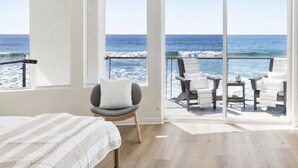 Une chambre avec un lit, une chaise et un balcon donnant sur l’océan.