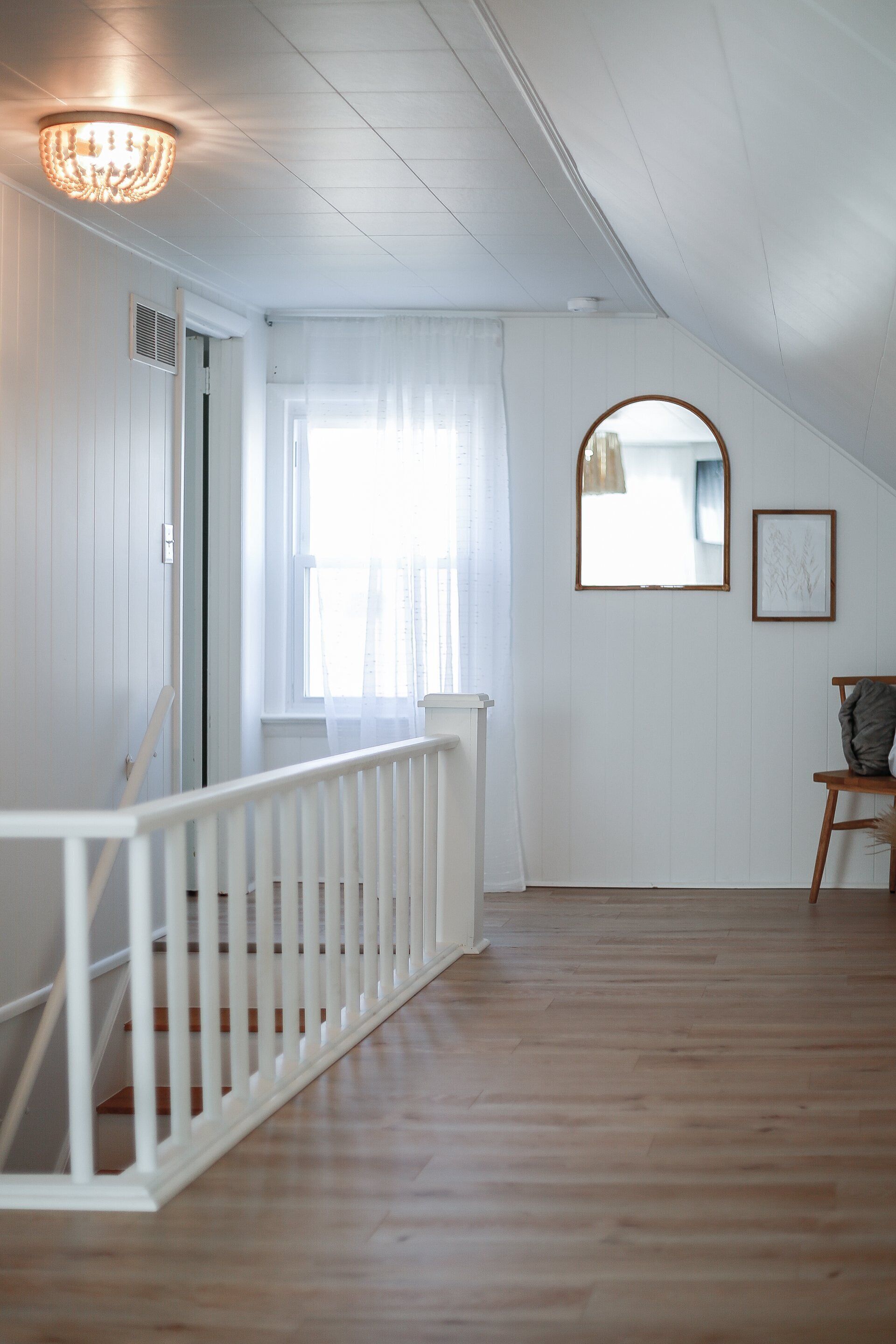 A staircase with white railings leading to a room with white walls and a wooden floor.