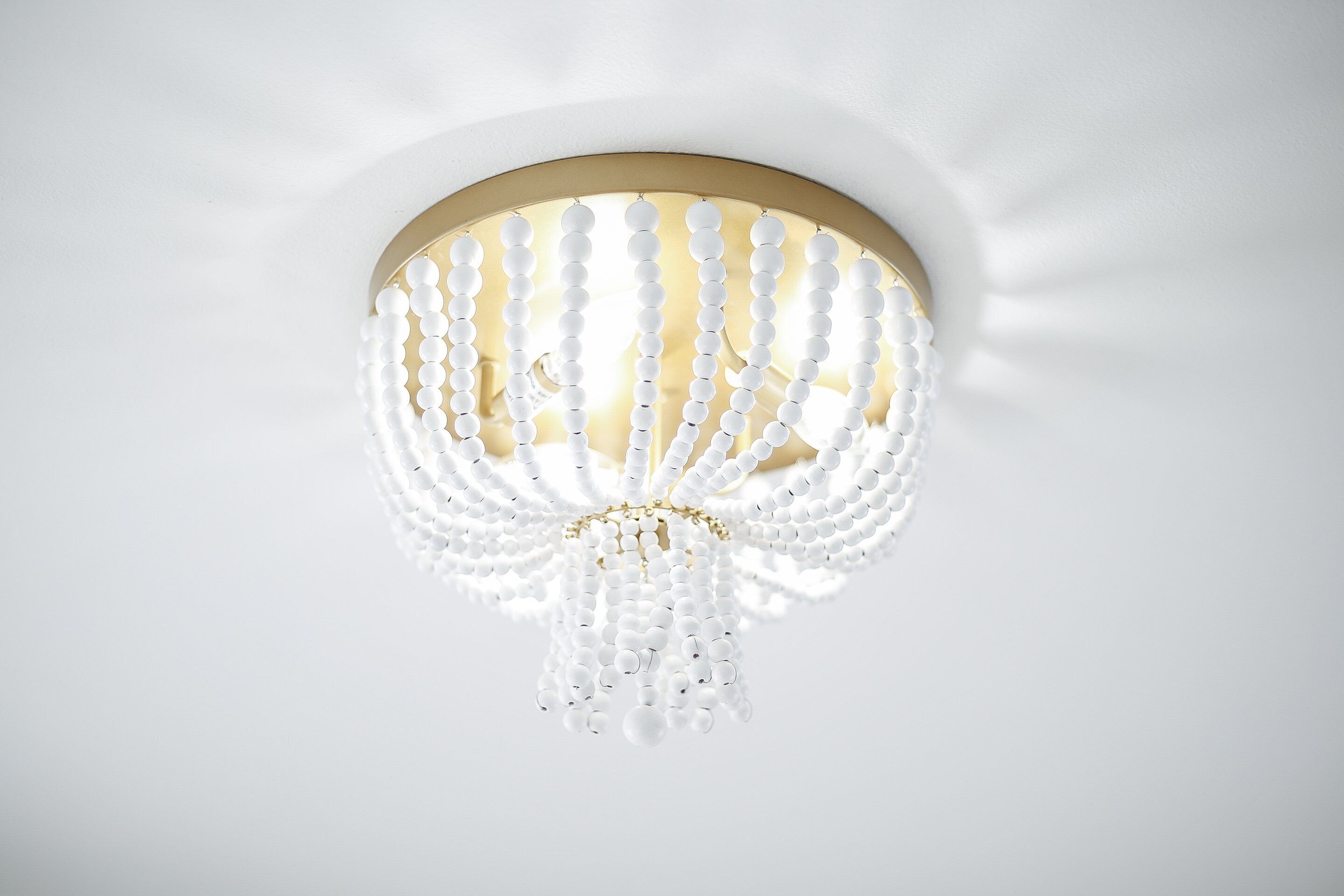 Ein Kronleuchter mit goldener Rahmung und weißen Perlen.