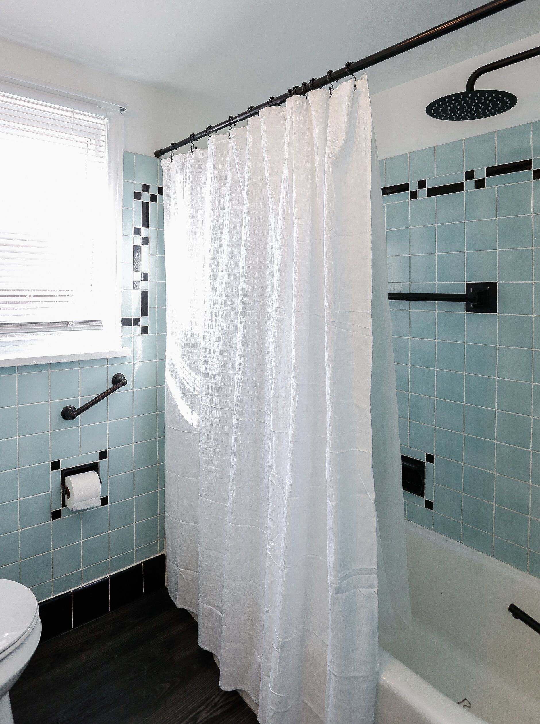 A bathroom with a shower curtain, a toilet, a towel rack, and a shower head.