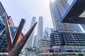 Un paysage urbain moderne, avec de hauts immeubles, une sculpture remarquable et un ciel dégagé.