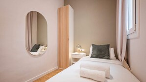 Ein Schlafzimmer mit einem Bett, einem Nachttisch, einer Lampe, einem Spiegel und einem Kleiderschrank.