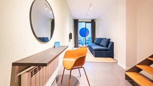 A modern living room with a sofa, a dining area with a table and chairs, and a large mirror on the wall. - Sweett | Girona B1 - Two Bedroom Apartment, Sleeps 5 (Barcelona)