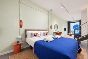 A modern hotel room with a bed, a nightstand, a desk, and a view of the outside.