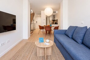 Un salon moderne avec un canapé bleu, une table basse en bois et un coin repas avec des chaises.