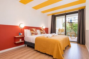 Una habitación de hotel con cama, mesita de noche, ventana con cortinas y vistas al exterior.