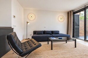 A modern living room with a sofa, a leather chair, a coffee table, and two wall-mounted lights.