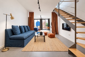 A modern living room with a sofa, coffee table, and a staircase. - Sweett | Girona B2 - Four Bedroom Apartment, Sleeps 10 (Barcelona)