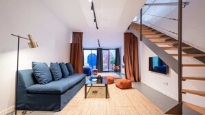Un salon moderne avec un canapé, une table basse et un escalier.