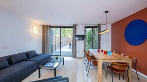 Un salon moderne comprenant un canapé, une table basse et un coin repas avec des chaises et une table.