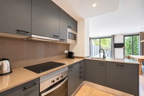 Una cocina moderna con armarios grises, microondas integrado, estufa y lavaplatos.
