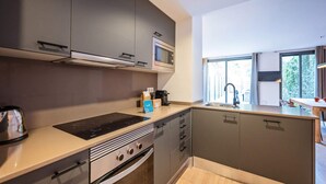 Une cuisine moderne avec des meubles gris, un four à micro-ondes encastré, une plaque de cuisson et un évier.
