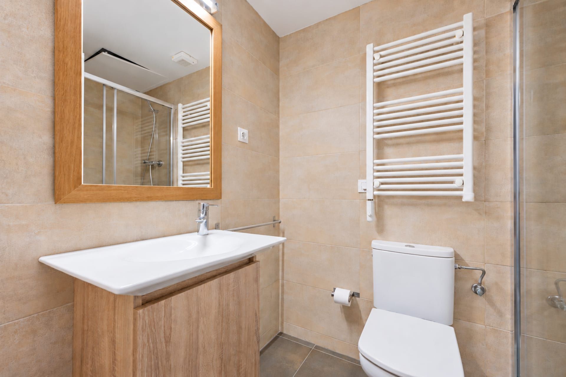 A bathroom with a white sink, a toilet, a shower, and a towel rack.