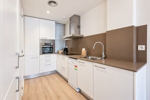 Une cuisine moderne avec des armoires blanches, des appareils en acier inoxydable et un comptoir brun.