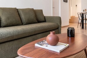 A living room with a sofa, a coffee table, a vase, and a book.