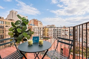 Un balcon avec une table, deux verres contenant une boisson jaune et un panneau bleu.