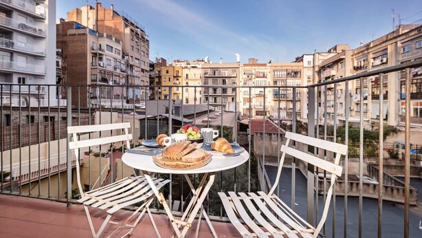 Ein Balkon mit einem Frühstückstisch, mit Blick auf eine Skyline mit mehreren Gebäuden.