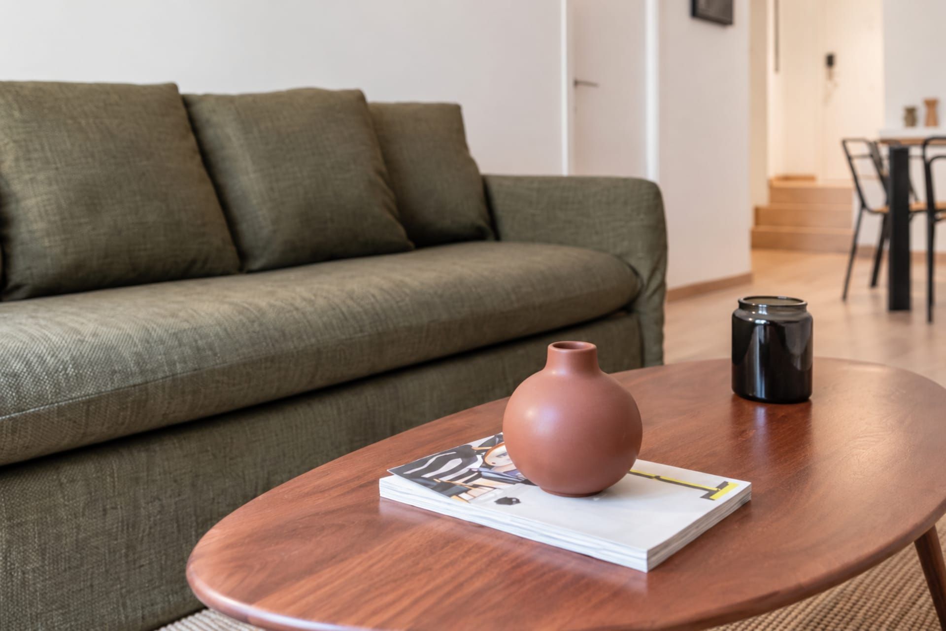 Ein Wohnzimmer mit einer Couch, einem Couchtisch, einer Vase und einem Buch.