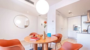 A modern dining area with a round wooden table, orange chairs, and a mirror on the wall. - Sweett | Girona 402 - One Bedroom Apartment, Sleeps 4 (Barcelona)