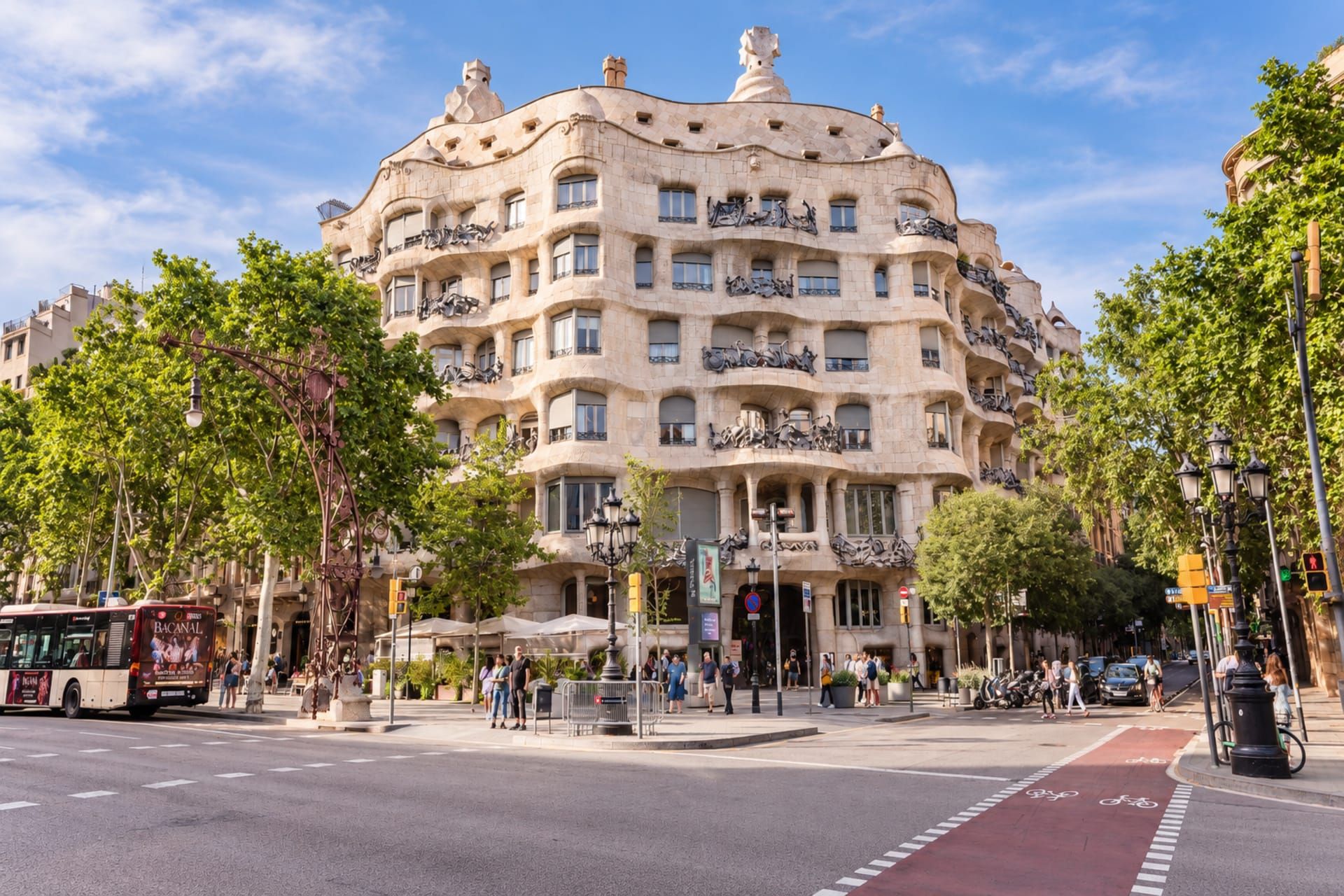 Un edificio de varios pisos con balcones, una calle en la parte delantera y árboles.