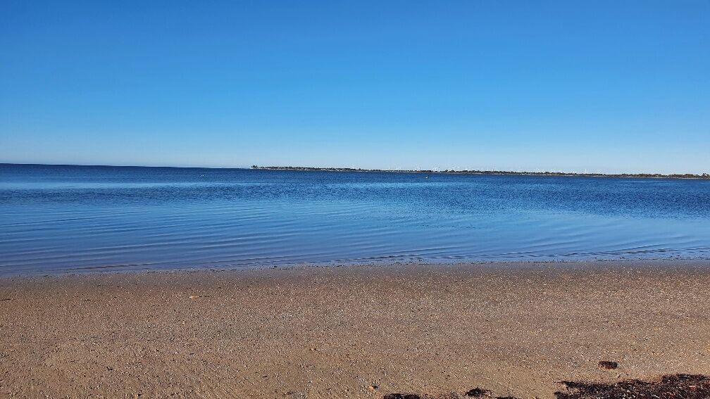 Une plage où l’eau est calme et le ciel est dégagé.