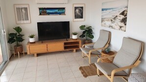 Olohuoneessa on taulutelevisio, puinen mediakeskus, kaksi rottinkituolia ja ruukkukasveja.