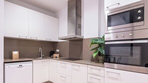 A modern kitchen with white cabinets, stainless steel appliances, a dishwasher, and a potted plant. - Sweett | Girona 501 - Three Bedroom Apartment, Sleeps 7 (Barcelona)