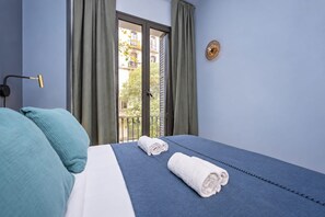 Een hotelkamer met een bed, een raam met gordijnen, een wandlamp en uitzicht op buiten.