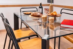 Een tafel met glazen blad, een fles wijn, croissants en koffiekopjes.