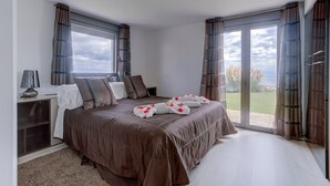 A bedroom with a large bed, a bedside table, a lamp, and a view through the glass door. - Villa "Atalaya" with Sea View, Private Pool & Wi-Fi (Peñíscola)