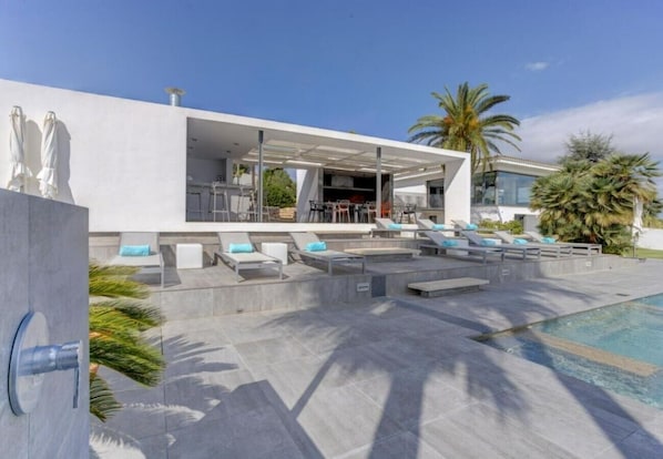 A modern outdoor pool area with lounge chairs and a covered seating area.