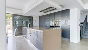 A modern kitchen with a central island, built-in appliances, and a staircase to the right. - Villa "Atalaya" with Sea View, Private Pool & Wi-Fi (Peñíscola)
