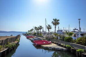 Un port de plaisance où des bateaux sont amarrés le long d’un cours d’eau paisible, entouré de palmiers et sous un ciel dégagé.