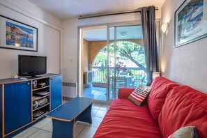 A living room with a red sofa, a blue entertainment unit, and a sliding glass door leading to an outdoor patio.