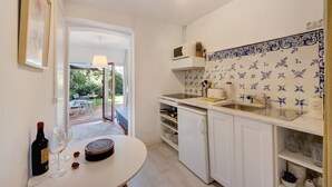 A kitchen with white cabinets, a sink, and a window overlooking a garden.