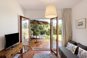 Un salon avec un téléviseur, un canapé et un coin repas équipé d’un parasol.