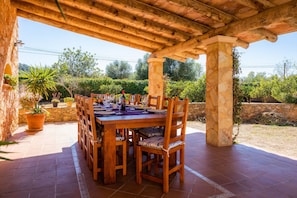 An outdoor wooden pergola with a dining table set for six, surrounded by chairs.