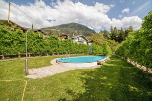 Una piscina rodeada por un césped cuidado, con una montaña al fondo.
