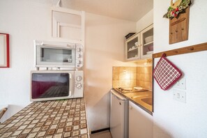 A compact kitchen with a microwave, oven, and a small refrigerator.