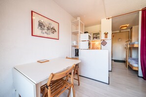 A compact kitchen with a white table and chairs, a refrigerator, and a microwave.