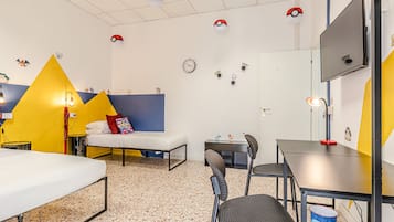 Ein Zimmer mit einem Bett, einem Schreibtisch, einem Sessel, einem Fernseher und einer Wanduhr.