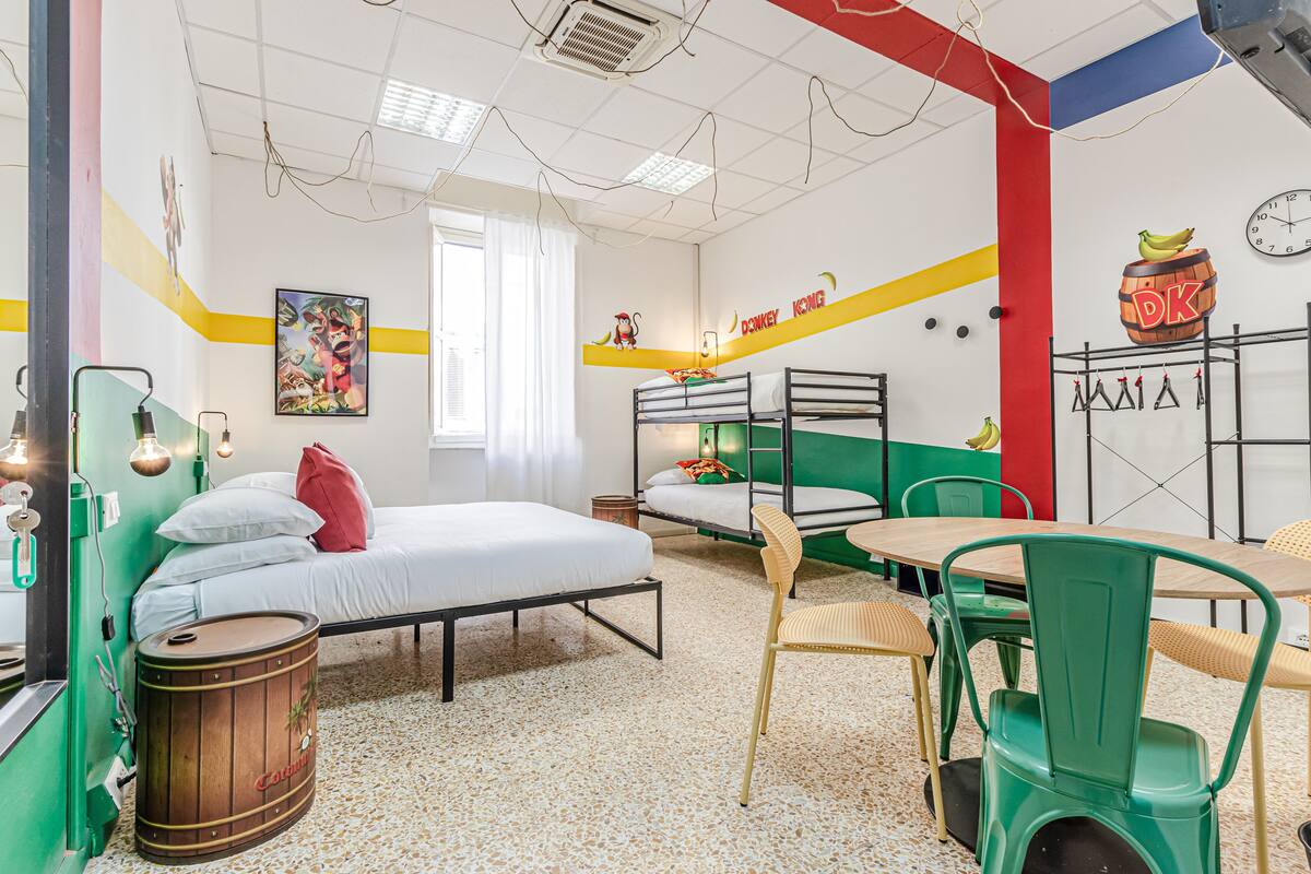 Una habitación con literas, una mesa, sillas, un tambor y un reloj de pared.