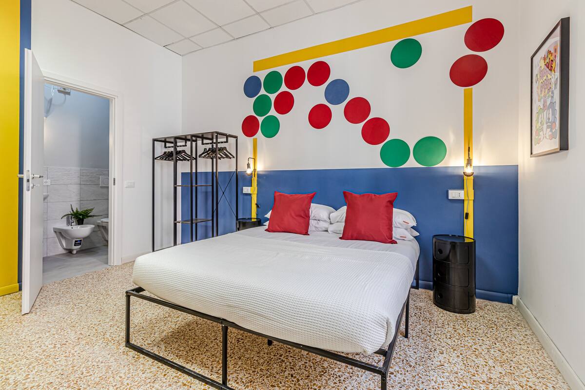 Un dormitorio con cama, armario, mesita de noche y una pared decorada con círculos de colores.