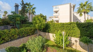 Una zona residencial con un muro de piedra, abundante vegetación y edificios modernos.